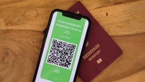 A physical passport next to a COVID-19 passport app on a smartphone.