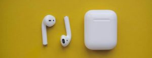 Accessoires mobiles : Une paire d'AirPods devant un fond jaune, l'un des accessoires mobiles les plus populaires de tous les temps.