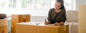 Liste de contrôle pour le déménagement - quelqu'un qui prépare une liste avec des cartons autour d'elle