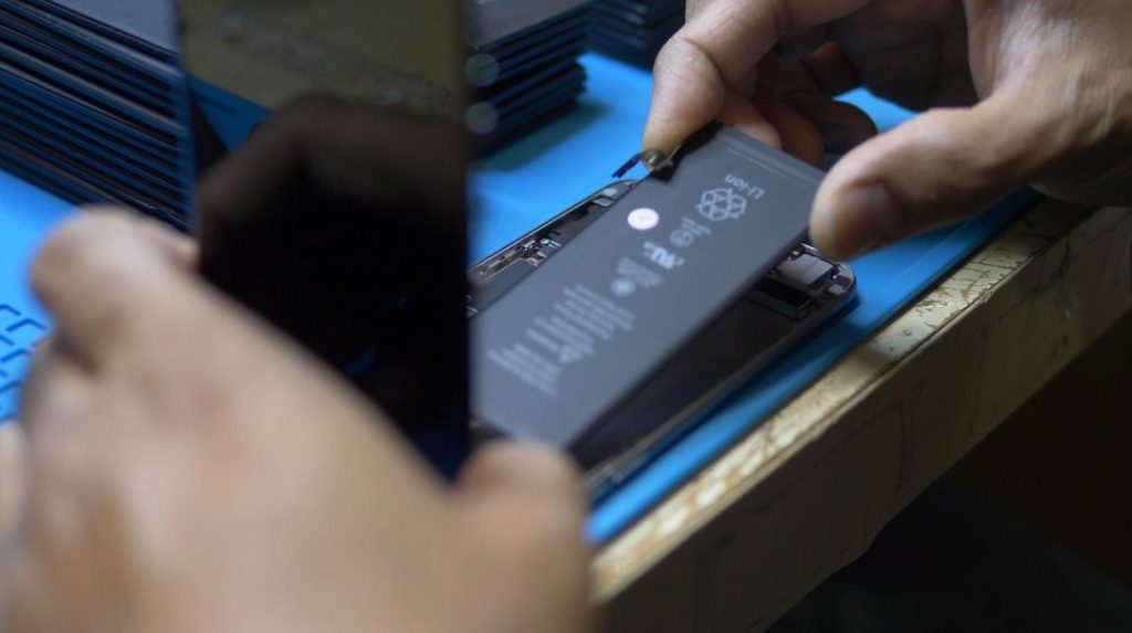 Technician repairing or replacing the battery inside a smartphone