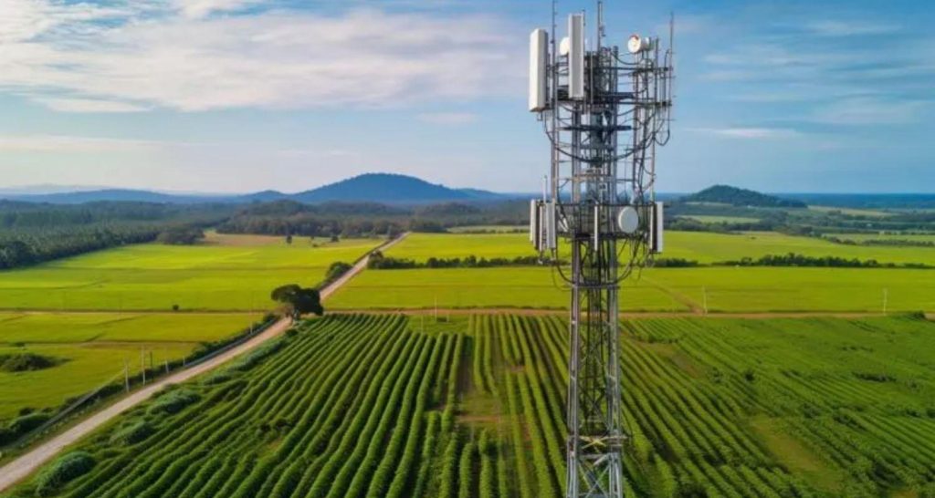 Tour de télécommunications entourée de champs et de forêts dans une région rurale.