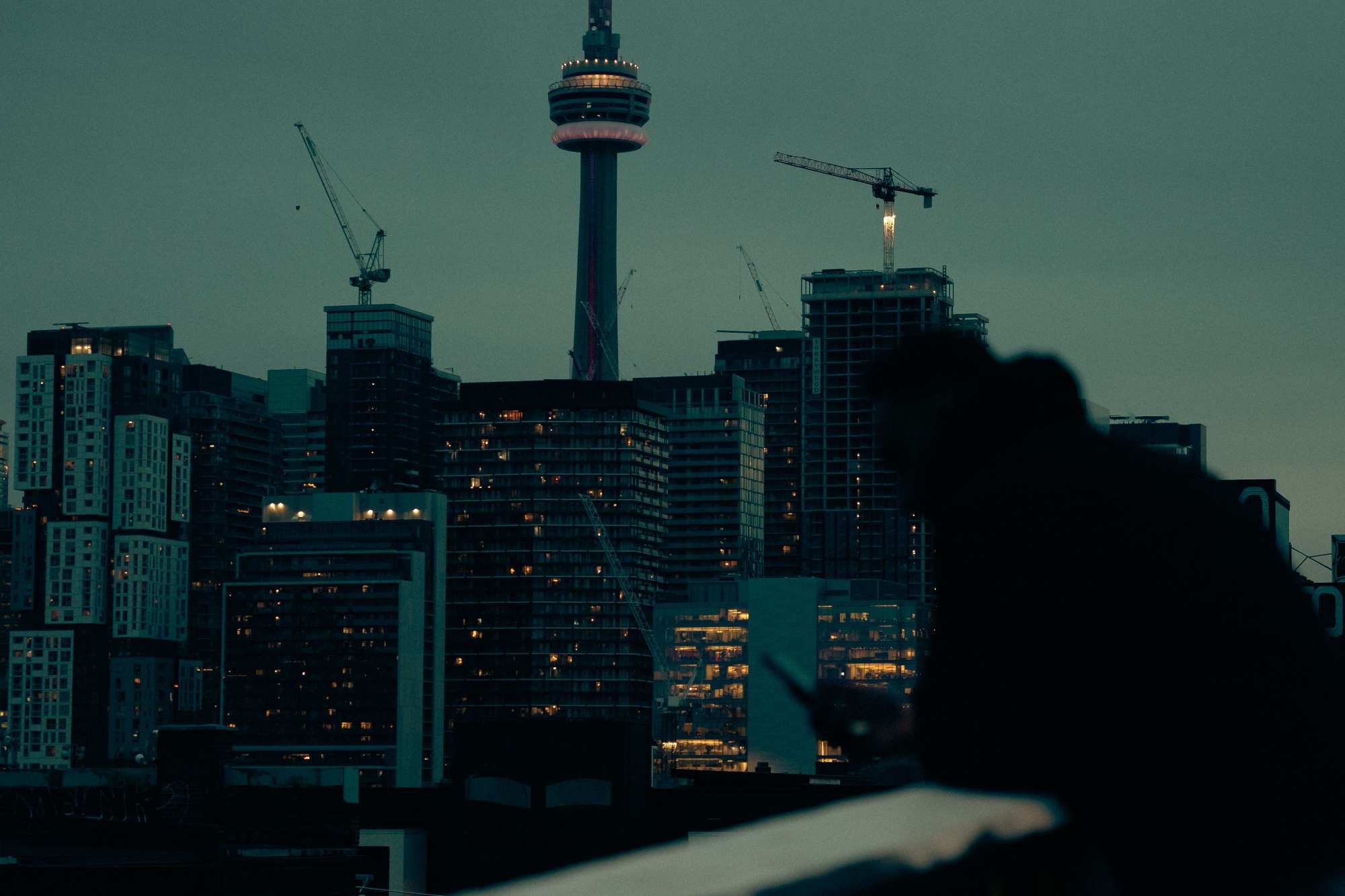 Vue du centre-ville de Toronto avec la Tour CN, des immeubles et des grues de construction au crépuscule.